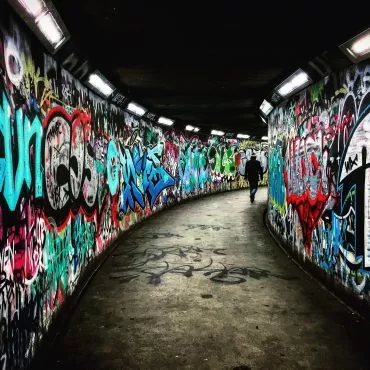 Querdenker - Person geht durch Unterführung mit Grafitti