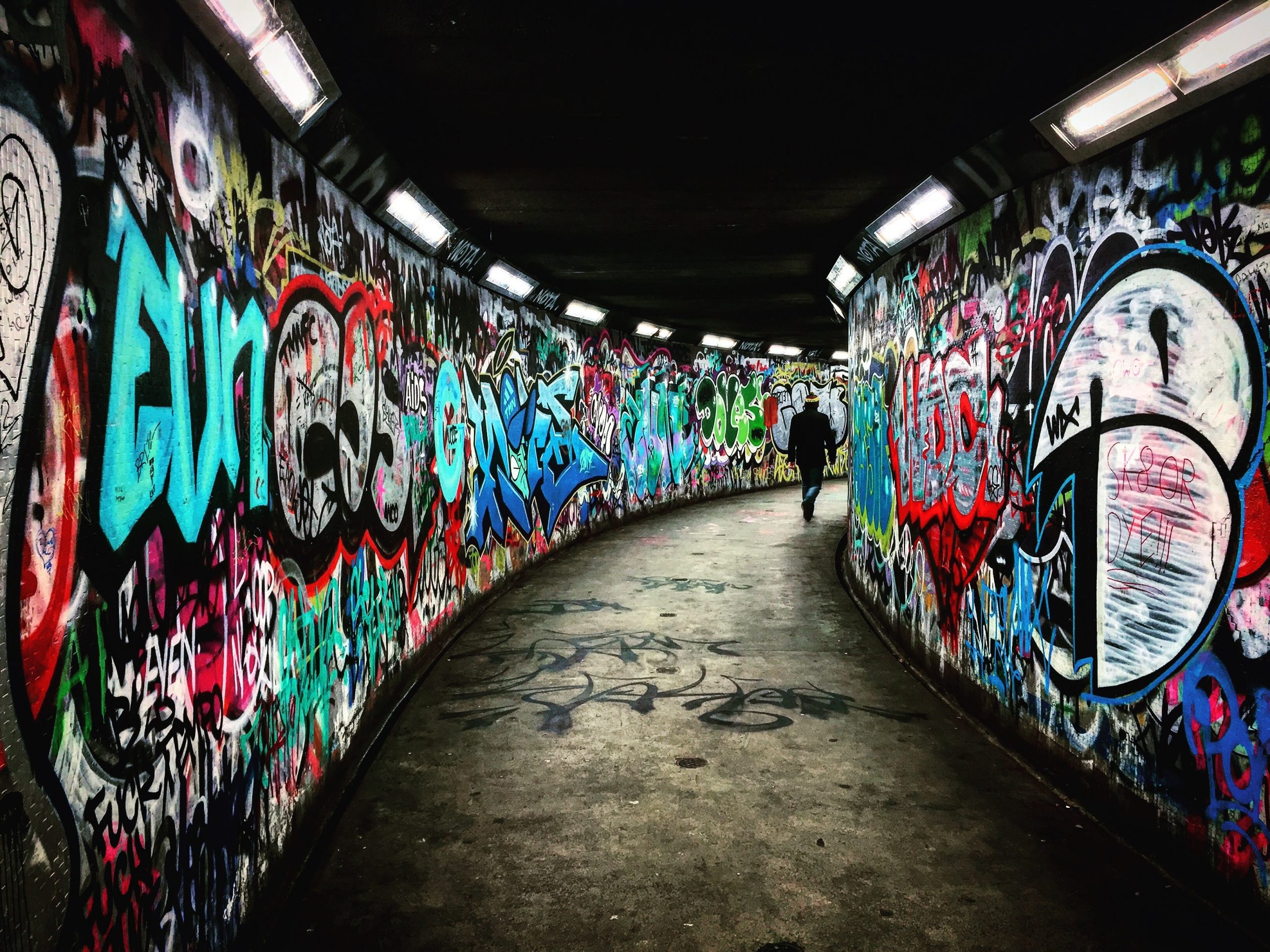 Querdenker - Person geht durch Unterführung mit Grafitti